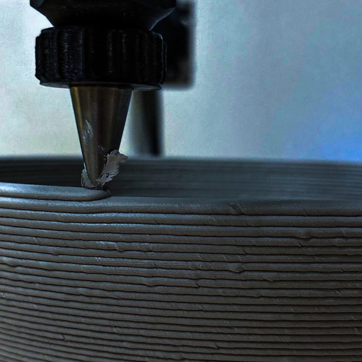 Clay, 3D-printed — the vessel rising line by line.